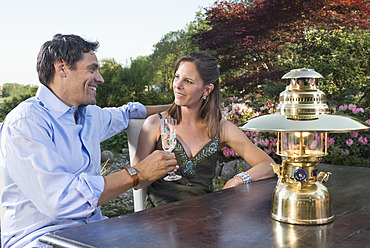 Germany, Bavaria, Couple enjoying drinks with lantern in foreground - RNF000643