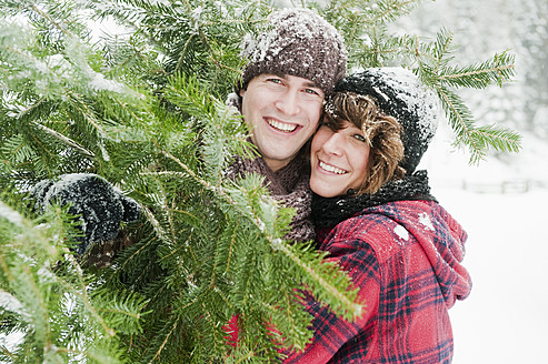 Austria, Salzburg Country, Flachau, Young man and woman holding christmas tree - HHF003630