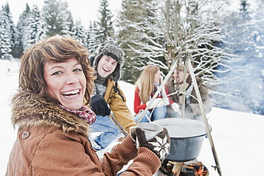 Österreich, Salzburger Land, Flachau, Junge Männer und Frauen sitzen am Kamin und machen Tee im Schnee - HHF003663