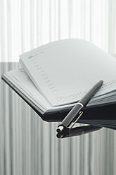 Close up of notebook and pen with reflection on table - ASF004374