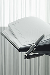 Nahaufnahme von Notizbuch und Stift mit Spiegelung auf dem Tisch - ASF004374