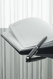 Nahaufnahme von Notizbuch und Stift mit Spiegelung auf dem Tisch - ASF004374