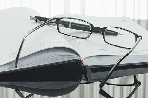 Nahaufnahme von Notizbuch, Stift und Brille mit Spiegelung auf dem Tisch - ASF004377
