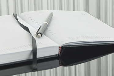 Close up of notebook and pen with reflection on table - ASF004378