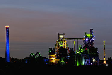 Germany, Nordrhein-Westfalen, Duisburg, Duisburg-Nord Landscape Park, View of illuminated blast furnace and smoke stacks of old industrial plant - FOF003421