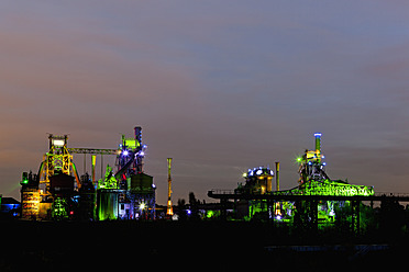 Deutschland, Nordrhein-Westfalen, Duisburg, Landschaftspark Duisburg-Nord, Blick auf beleuchteten Hochofen und Schornsteine einer alten Industrieanlage - FOF003422