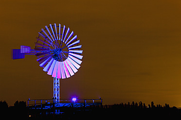 Germany, Nordrhein-Westfalen, Duisburg, Duisburg-Nord Landscape Park, View of illuminated wind mill of industrial plant at night - FOF003424