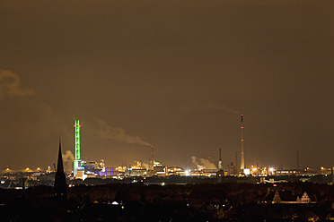 Germany, Nordrhein-Westfalen, Duisburg, View of illuminated green tower and industrial plant at night - FOF003425