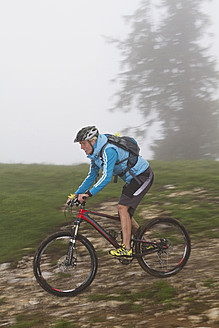 Germany, Bavaria, Chiemgau, Mid adult woman moutainbiking in fog - FFF001200