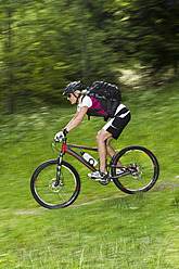 Deutschland, Bayern, Schliersee, Mid erwachsene Frau moutainbiking auf Gras - FFF001202