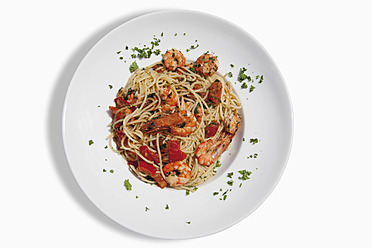 Close up of spaghetti with scampis fried in chili oil, tomato and herbs against white background - CSF015272