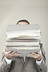 Close up of mature businessman at office holding stack of file - MAEF003433