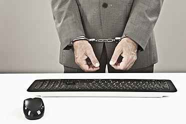Close up of businessman standing near keyboard with hand's cuffed - MAEF003451