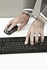 Close up of businessman's hand cuffed while cyber crime - MAEF003452