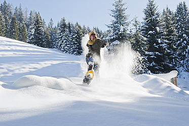 Österreich, Salzburger Land, Flachau, Junge Frau mit Schneeschuhen geht im Schnee - HHF003693