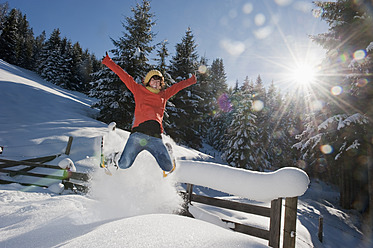 Österreich, Salzburger Land, Flachau, Junge Frau mit Schneeschuhen springt im Schnee - HHF003695