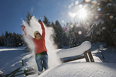 Austria, Salzburg Country, Flachau, Young woman wearing snow shoes jumping in snow - HHF003696