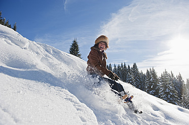 Austria, Salzburg Country, Flachau, Young woman tobogganing in snow - HHF003702