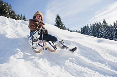 Österreich, Salzburger Land, Flachau, Junge Frau beim Rodeln im Schnee - HHF003703