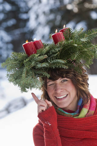 Österreich, Salzburger Land, Flachau, Nahaufnahme einer jungen Frau mit Adventskranz auf dem Kopf im Winter, lizenzfreies Stockfoto