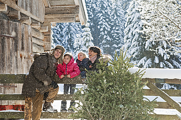 Österreich, Salzburger Land, Flachau, Familie lehnt an Zaun im Schnee - HHF003723