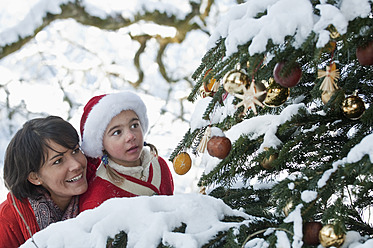 Austria, Salzburg Country, Flachau, Young mother and daughter looking at christmas tree - HHF003724