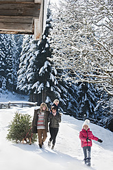 Österreich, Salzburger Land, Flachau, Blick auf Familie mit Weihnachtsbaum und Schlitten im Schnee - HHF003727