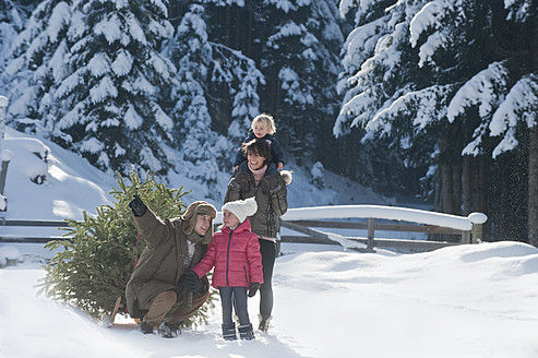 Österreich, Salzburger Land, Flachau, Blick auf Familie mit Weihnachtsbaum und Schlitten im Schnee - HHF003733