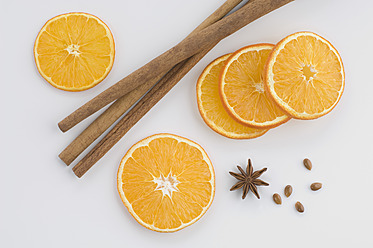 Close up of orange slice with star anise and cinnamon against white background - CRF002073