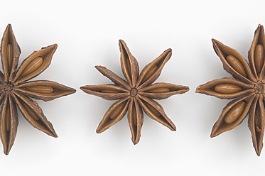 Close up of three star anise against white background - CRF002075