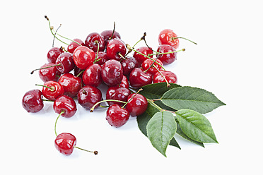 Close up of cherries with leaves on white background - MAEF003489