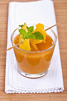 Nahaufnahme von Mango-Smoothie mit Minze und Mangoscheibe am Cocktailstick - TSF000320