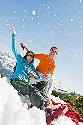 Austria, Salzburg Country, Altenmarkt-Zauchensee, Mid adult couple sitting in winter snow and having fun - HHF003760