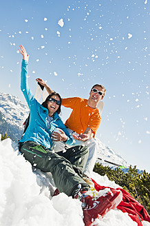 Österreich, Salzburger Land, Altenmarkt-Zauchensee, Mid adult couple sitting in winter snow and having fun - HHF003760
