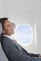 Deutschland, Bayern, München, Mittlerer Erwachsener Geschäftsmann entspannt sich in der Business-Class-Flugzeugkabine - WESTF016791