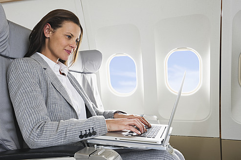 Deutschland, Bayern, München, Mittlere erwachsene Geschäftsfrau mit Laptop in der Business-Class-Flugzeugkabine - WESTF016795