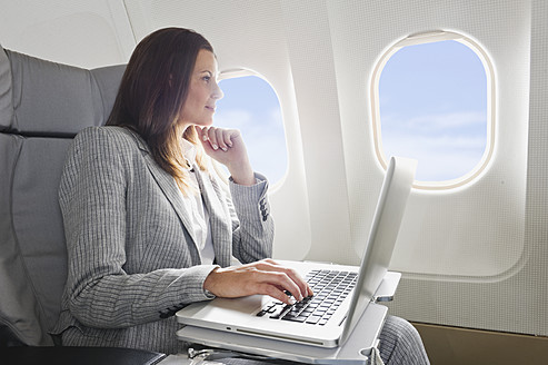 Deutschland, Bayern, München, Mittlere erwachsene Geschäftsfrau mit Laptop in der Business-Class-Flugzeugkabine - WESTF016800