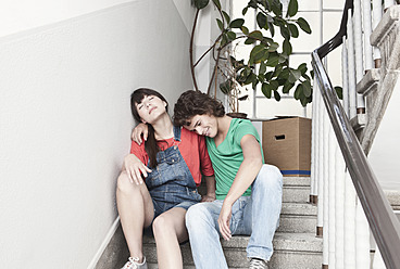 Germany, Cologne, Young couple resting on stairway in renovating apartment - FMKF000284