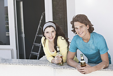 Deutschland, Köln, Junges Paar trinkt Bier in Wohnung - FMKF000285