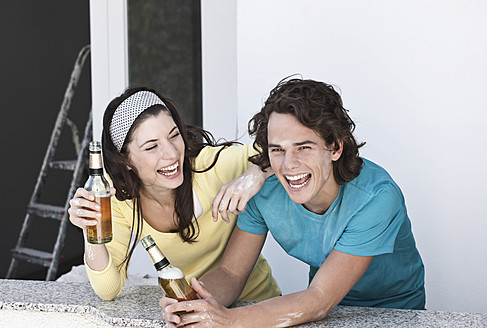 Deutschland, Köln, Junges Paar trinkt Bier in Wohnung - FMKF000287