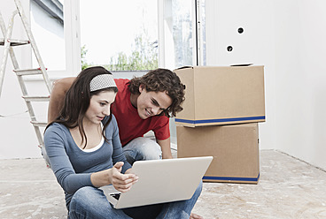 Germany, Cologne, Young couple using laptop in renovating apartment - FMKF000288