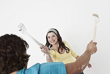 Germany, Cologne, Young couple having fun with paint brush in renovating apartment - FMKF000299