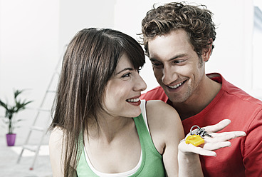 Deutschland, Köln, Nahaufnahme eines jungen Paares mit Hausschlüsseln bei der Renovierung einer Wohnung, lächelnd - FMKF000343