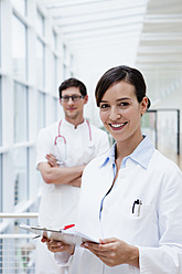 Germany, Bavaria, Diessen am Ammersee, Two young doctors with clip board and pen, smiling - JRF000209