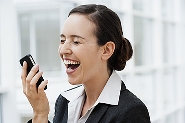 Deutschland, Bayern, Diessen am Ammersee, Junge Geschäftsfrau mit Mobiltelefon in der Hand, Nahaufnahme, lachend - JRF000281