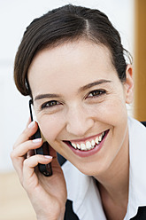 Deutschland, Bayern, Diessen am Ammersee, Nahaufnahme einer jungen Geschäftsfrau, die mit einem Handy telefoniert, lächelnd, Portrait - JRF000288