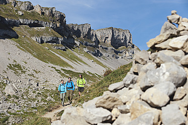 Austria, Kleinwalsertal, Group of people hiking on mountain trail with stack of stones in foreground - MIRF000224