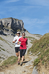 Österreich, Kleinwalsertal, Mann und Frau laufen auf Bergpfad - MIRF000229