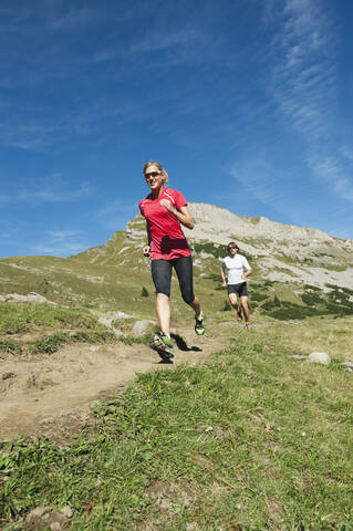 Österreich, Kleinwalsertal, Mann und Frau laufen auf Bergpfad, lizenzfreies Stockfoto