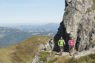 Austria, Kleinwalsertal, Man and woman hiking near rocks on mountain - MIRF000240